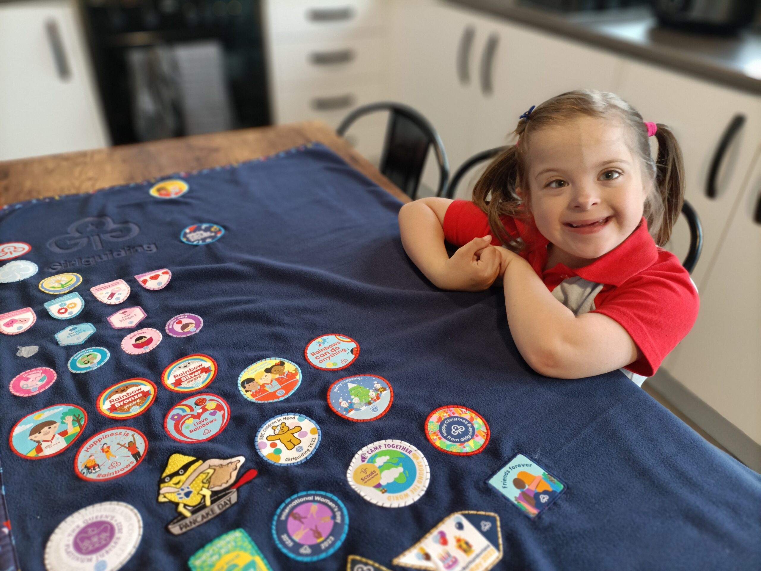 Girl smiling with rainbow badges on table